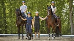 Katharina Hemmer, Gianna Regenrecht, Antonia Baumgart und Anna Den im Gruppenfoto mit zwei Pferden auf einem Reitplatz