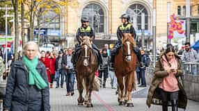 CAVALLO Polizei Reiterstaffel Hannover, zwei Polizistinnen unterhalten sich reitend auf Kaltblutpferden in Fußgängerzone vor dem Bahnhof, viele Passanten ringsherum, Frau mit Handy im Vordergrund