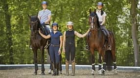 Katharina Hemmer, Gianna Regenrecht, Antonia Baumgart und Anna Den im Gruppenfoto mit zwei Pferden auf einem Reitplatz