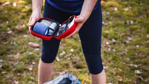 Erste-Hilfe-Set, Notfall Frau öffnet Erste-Hilfe-Set im Wald