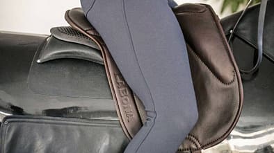 Frau mit Reithose sitzt auf einem Reitpad