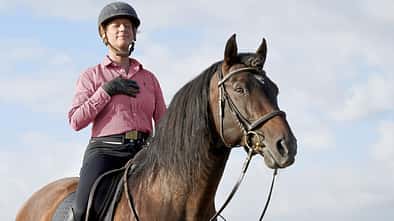 CAVALLO Die Kraft des Atmens, Reiterin konzentriert sich auf Atem mit geschlossenen Augen und Hand auf der Brust auf Pferd