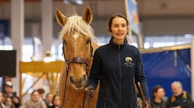 Live-Vorführung einer Trainerin mit Pferd an der Hand