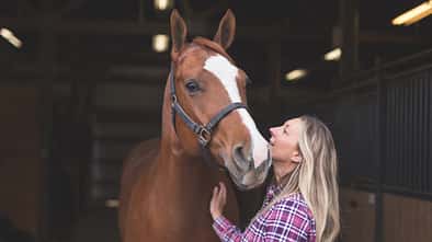 Eine Frau mit ihrem Pferd im Stall.