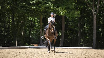 Anna Den und ihr Dunkelbrauner Feiner Prinz auf einem Dressurviereck im Freien in Warendorf.