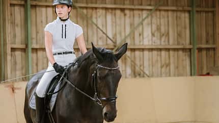 Teenager-Dressur-Reiterin in der Reithalle zum Turnier