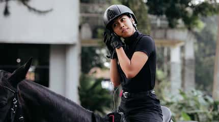 Eine junge Frau verkabelt ihren C-Coach auf dem Pferd vor dem Reitunterricht.