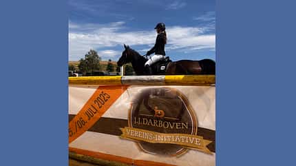 Banner von J.J. Darboven Vereins-Initiative, dahinter eine Reiterin im Turnieroutfit.