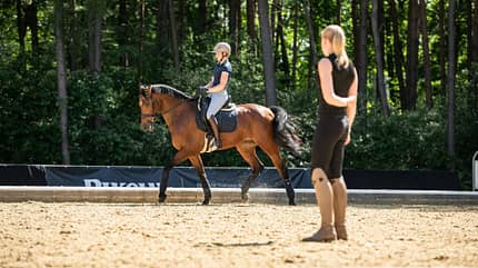 Reittraining, Reiterin, Pferd, Trainerin, Helm, Dressur, Sandplatz, Warendorf, Cavallo, Ridingtogether, Reitunterricht, Reitstunde, Coaching, Reitlehrer, Training, Dressur Reittraining auf einem Sandplatz: Antonia Baumgart trabt mit Stute Kelly Rose, Katharina Hemmer beobachtet.