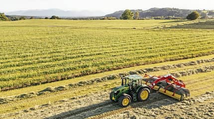 Traktor, Feldarbeit, Ernte, Landwirtschaft, Luftaufnahme, Schlepper, Agrartechnik, Teff-Ernte, Grünfutter, Ackerbau, Heuernte Luftaufnahme eines Traktors bei der Heuernte auf einem Feld, im Hintergrund Wiesen und Hügel.