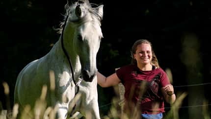 Marlitt Wendt mit einem Schimmel auf der Wiese 