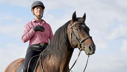 CAVALLO Die Kraft des Atmens, Reiterin konzentriert sich auf Atem mit geschlossenen Augen und Hand auf der Brust auf Pferd