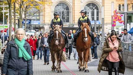 CAVALLO Polizei Reiterstaffel Hannover, zwei Polizistinnen unterhalten sich reitend auf Kaltblutpferden in Fußgängerzone vor dem Bahnhof, viele Passanten ringsherum, Frau mit Handy im Vordergrund