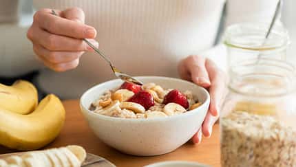 Eine Frau isst ein Haferflocken-Porridge mit einem Obst-Topping