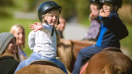 Kinder beim Ponyreiten in der Gruppe