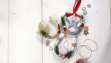 Weihnachtliche Deko-Hufeisen auf hellem Holzuntergrund