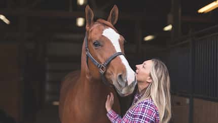 Eine Frau mit ihrem Pferd im Stall.