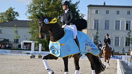 Vorjahressiegerin Dominique Filion (NED) mit ihrem Pferd The Boss, welcher eine hellblaue Paradedecke trägt, zur Ehrenrunde beim Neustädter Pferdesommer 2025.