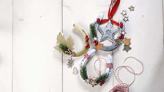 Weihnachtliche Deko-Hufeisen auf hellem Holzuntergrund