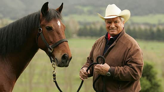Monty Roberts mit einem braunen Pferd an der Hand