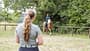 Reitunterricht, Reitstunde, Reiterin, Pferd, Reitplatz, Reithelm, Sattel, Pferdesport, Naturkulisse Das Foto zeigt eine Reiterin mit Reithelm auf einem Haflinger auf einem umzäunten Reitplatz. Im unscharfen Vordergrund steht eine Reitlehrerin, während Bäume und Wiese den natürlichen Hintergrund bilden.