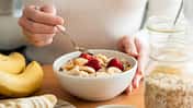 Eine Frau isst ein Haferflocken-Porridge mit einem Obst-Topping