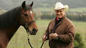 Monty Roberts mit einem braunen Pferd an der Hand